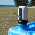 Blue water container with a white and black pump in an outdoor setting.